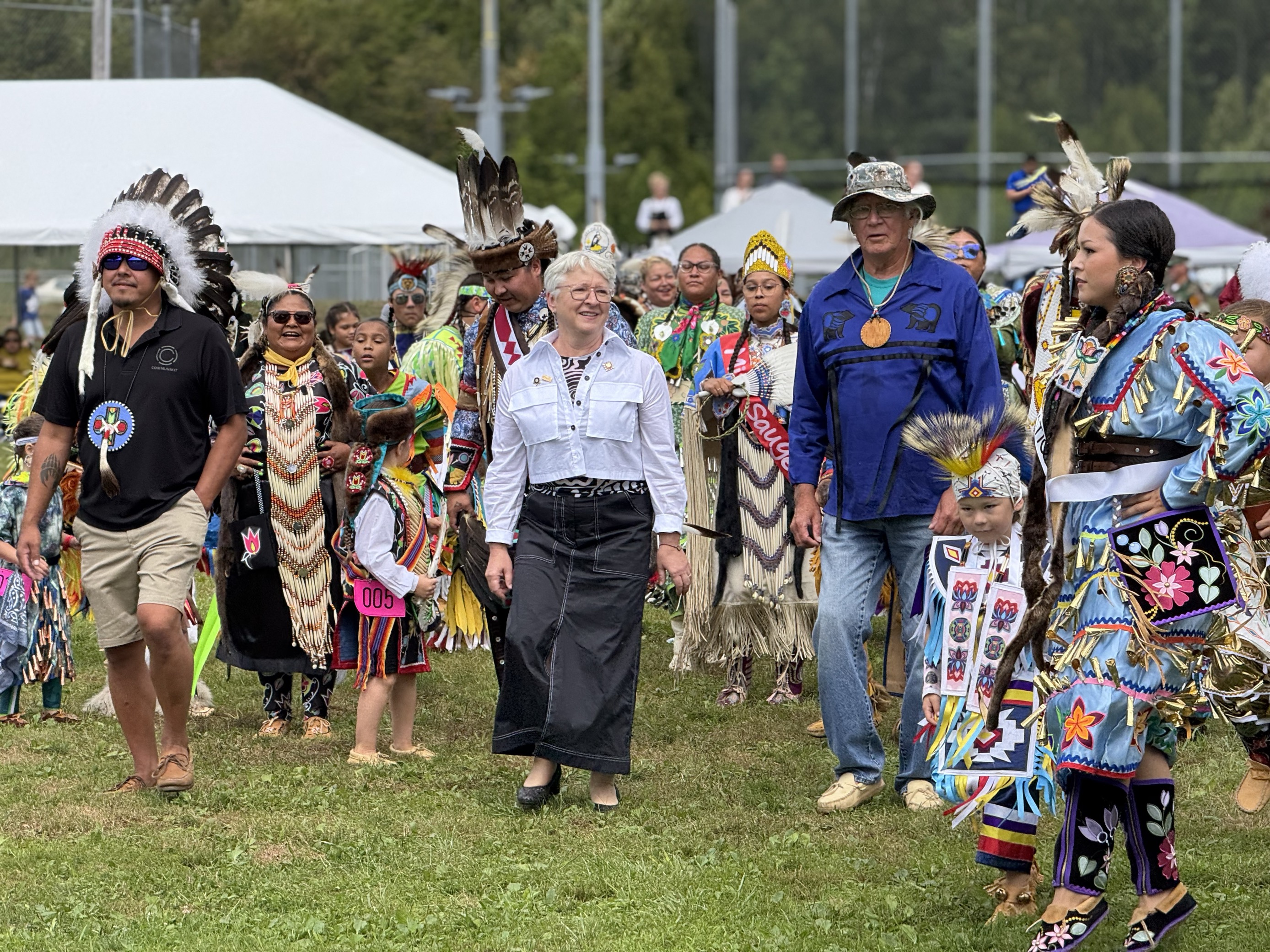L'honorable Edith Dumont marche avec des membres de la communauté au Pow Wow de la Première Nation de Saugeen